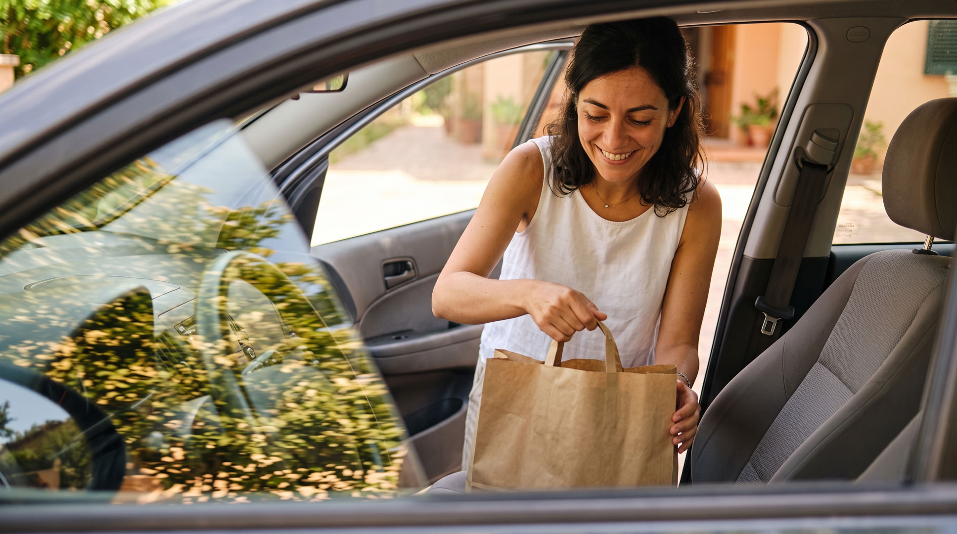Donna porta in casa la spesa dall'auto in una giornata estiva